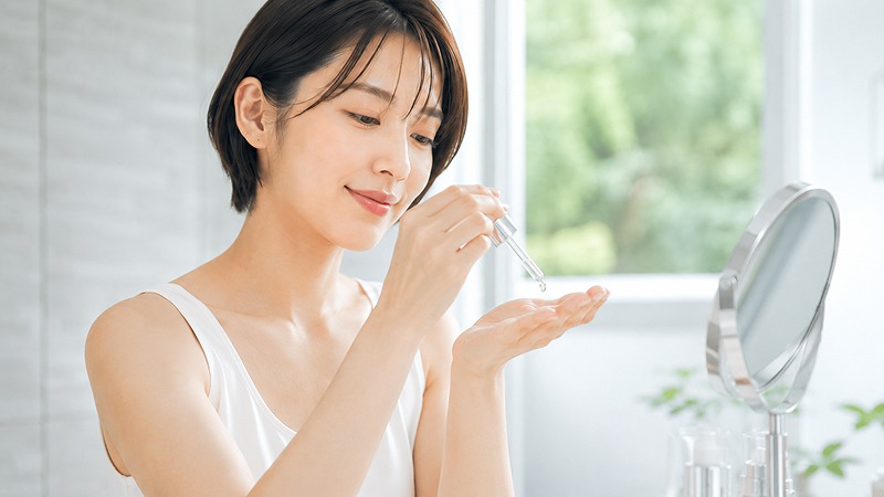 鏡で頬の毛穴や肌状態を確認する女性